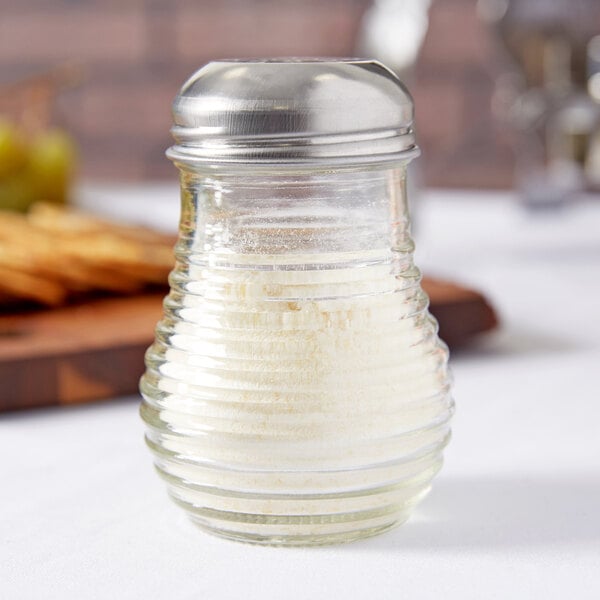 A glass cheese shaker with a chrome-plated metal lid.