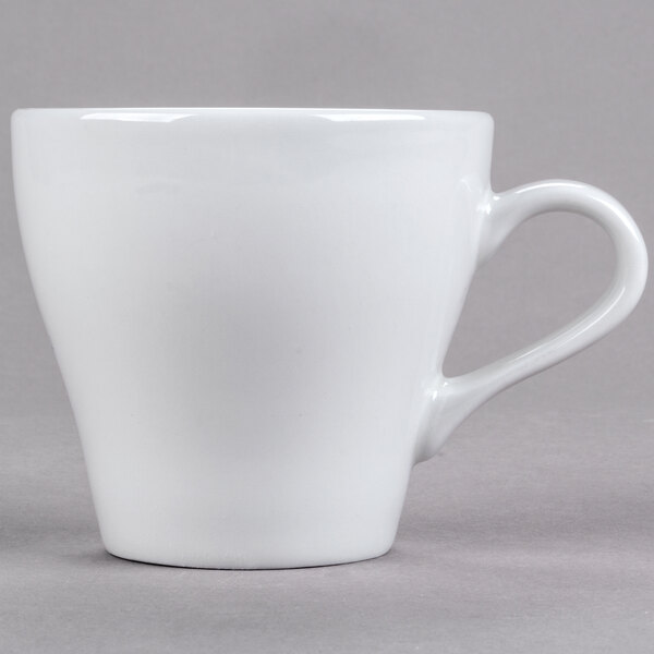 A close-up of a Tuxton white porcelain cappuccino mug with a handle.
