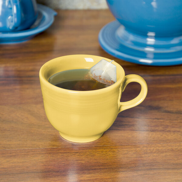 A yellow Fiesta china cup with a tea bag in it.
