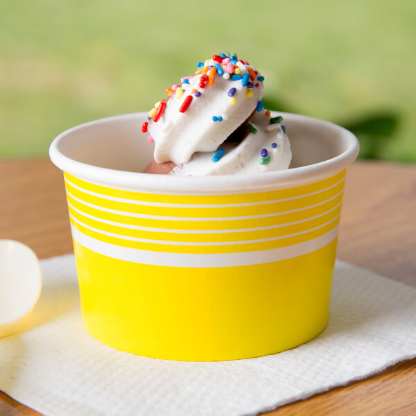 A yellow Choice paper cup with a scoop of frosted ice cream and sprinkles.
