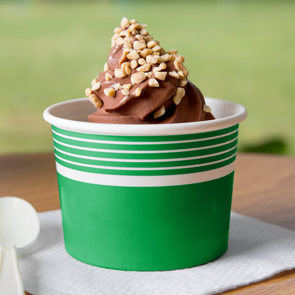 A green Choice paper cup filled with chocolate ice cream topped with nuts.