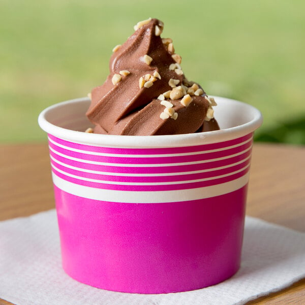 A pink Choice paper cup filled with chocolate ice cream topped with nuts.