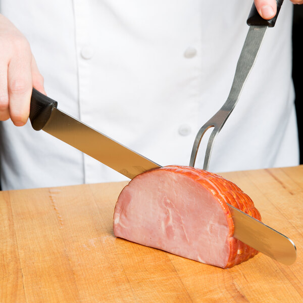 A person using a Mercer Culinary Millennia Straight Edge Slicer Knife to cut a piece of ham.