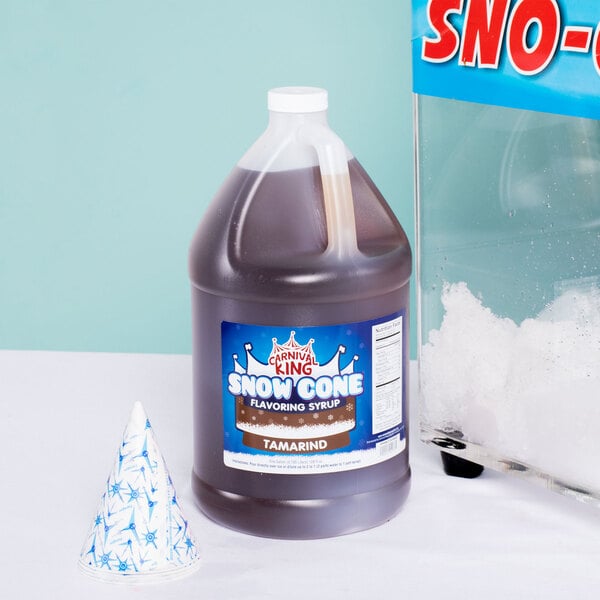 A bottle of Carnival King Tamarind Snow Cone Syrup next to a snow cone.