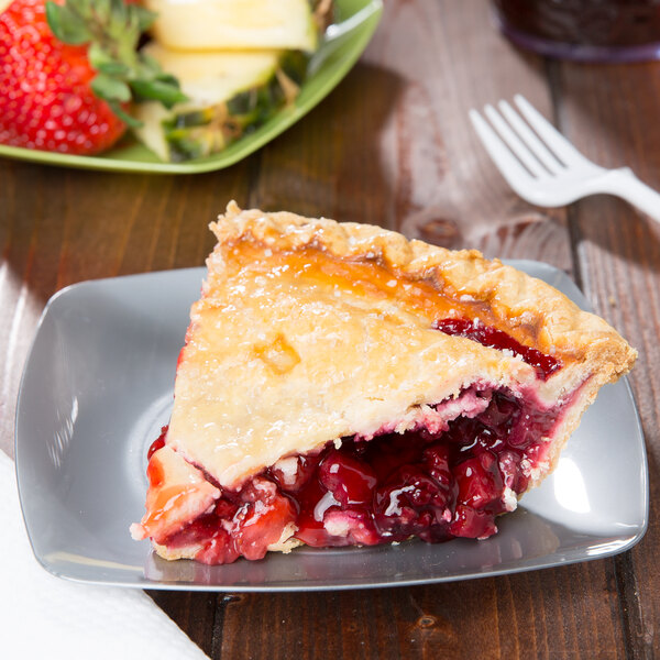 A square silver plastic dessert plate with a slice of cherry pie and berries.