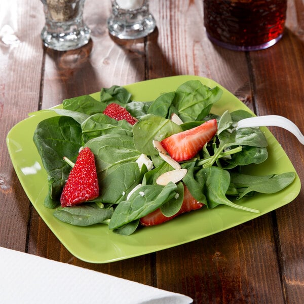 A green Fineline square salad plate with strawberries and spinach on it.