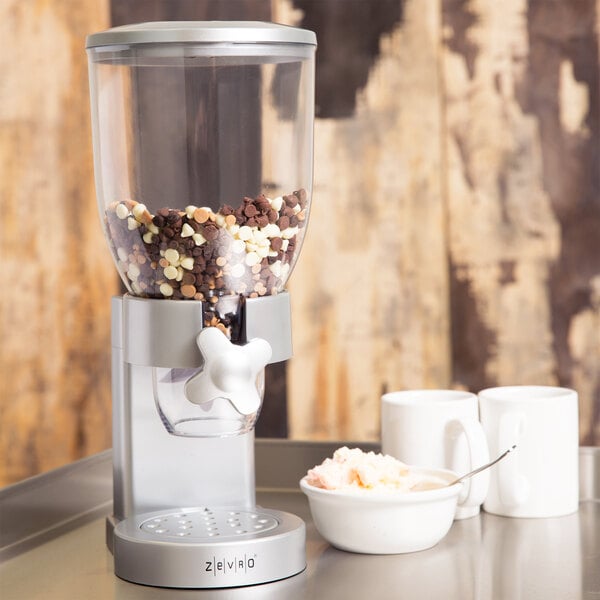 A Zevro silver dry food dispenser with food in it.