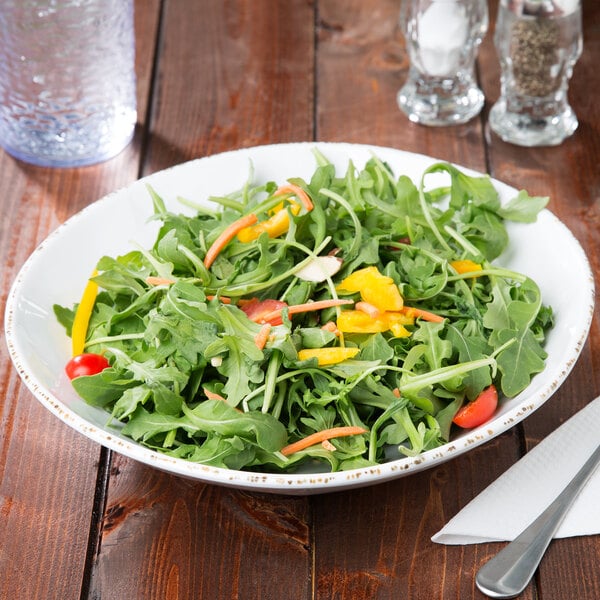 A bowl of salad with green vegetables on a table in a salad bar.