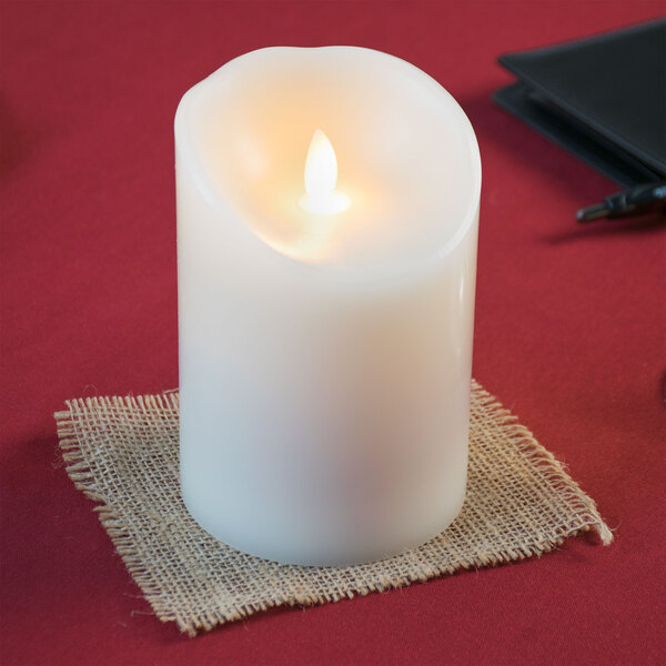 A close-up of a Sterno Mirage cream LED candle on a table.