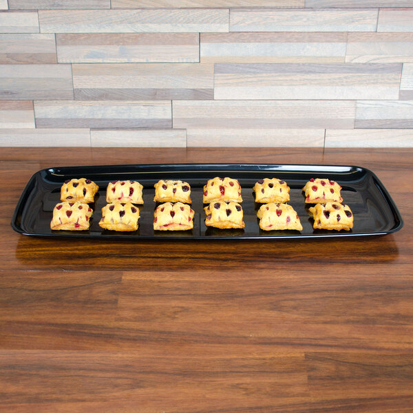 A tray of pastries on a black Sabert catering tray on a table.