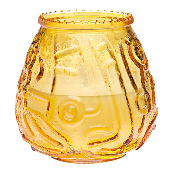 A yellow wax filled glass candle in a yellow glass vase with a pattern.