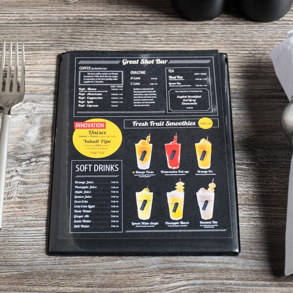 A black Menu Solutions Hamilton menu on a table with a drink.