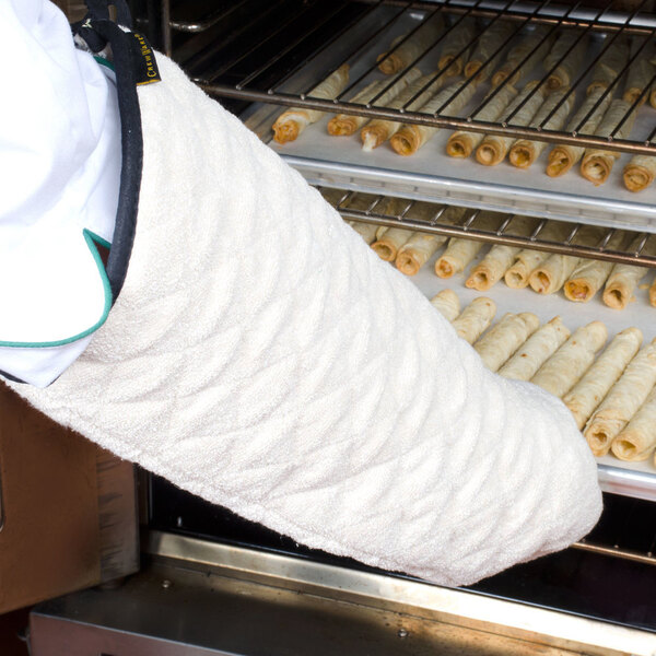 A person wearing San Jamar Terry Oven Mitts holds a baking tray.
