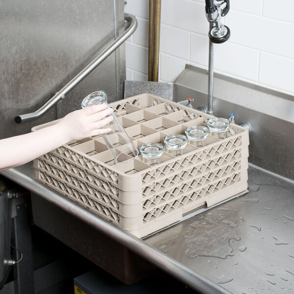 A woman uses a Vollrath beige Traex glass rack to hold a glass.