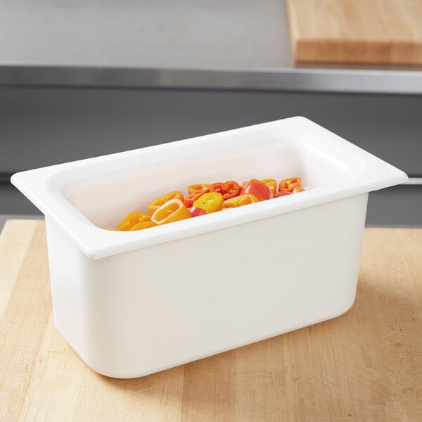 A Carlisle white plastic food pan filled with orange and yellow peppers.