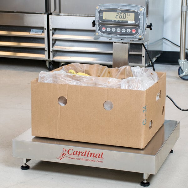 A cardboard box of food on a Cardinal Detecto electronic bench scale with a digital display.