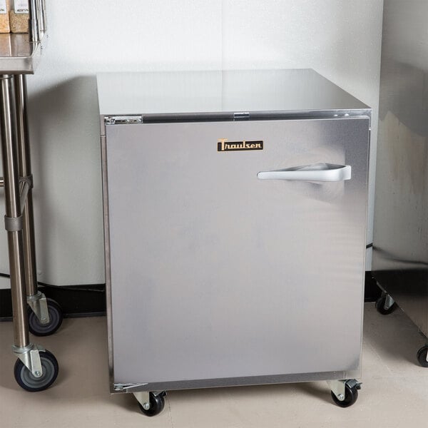 A Traulsen undercounter refrigerator with a left hinged door and wheels.