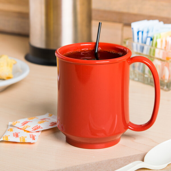 A close-up of a red GET Sensation Tritan mug on a table.