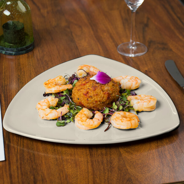 A GET Diamond Ivory triangular melamine plate with shrimp and a wine glass on a table.