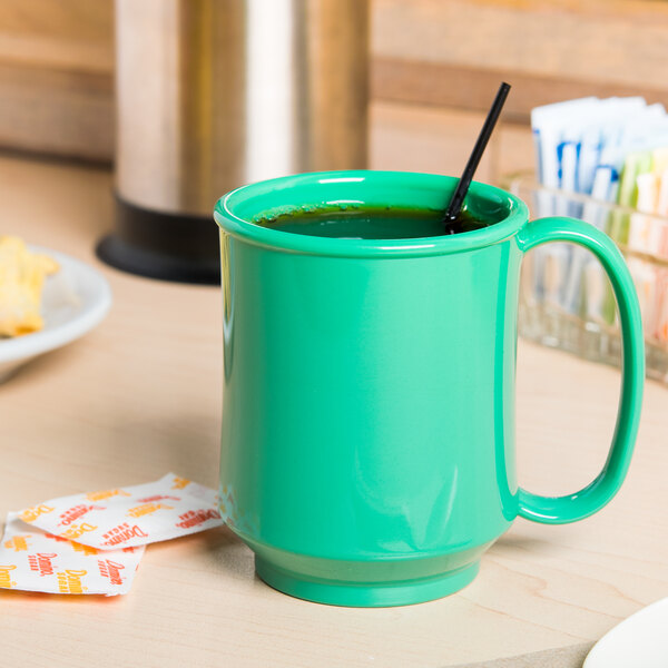 A green GET Rainforest Green Tritan mug with a black straw on a table.