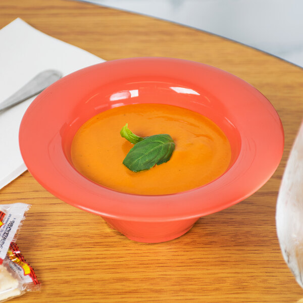A Rio orange melamine bowl filled with soup on a table.