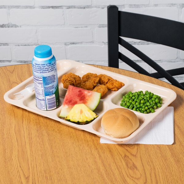 A tan polypropylene compartment tray with food on a table.