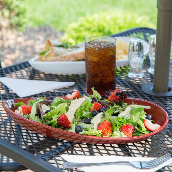 A table with a GET Osslo chili oval melamine platter holding salad and strawberries.