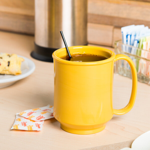 A yellow GET Tritan mug filled with liquid on a counter.