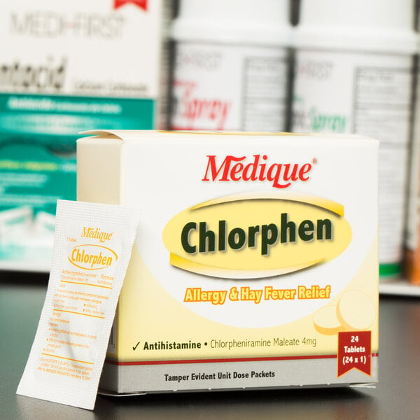 A white box of Medique Chlorphen allergy and hay fever relief tablets on a table next to other medicine boxes.