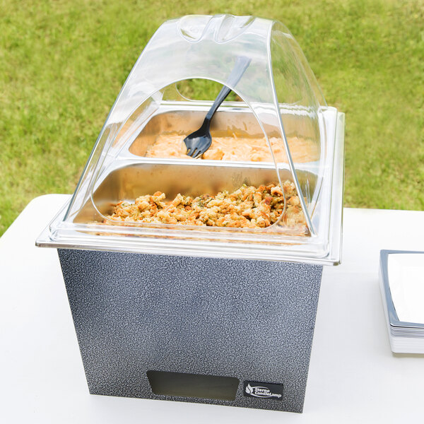 A Sterno silver vein chafer with food in it on a table outdoors.