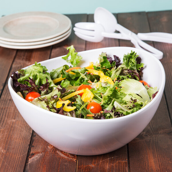 A white Osslo melamine bowl filled with salad with a white plastic spoon and fork.