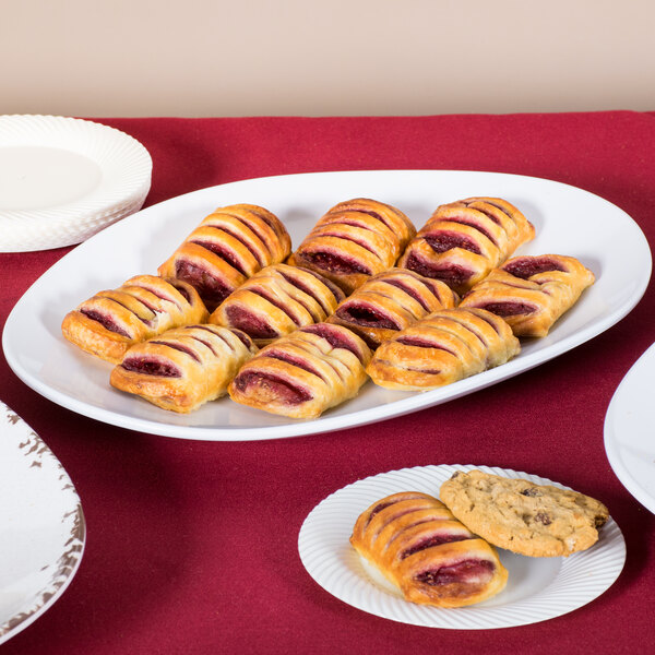 A white oval melamine platter with pastries on a table.