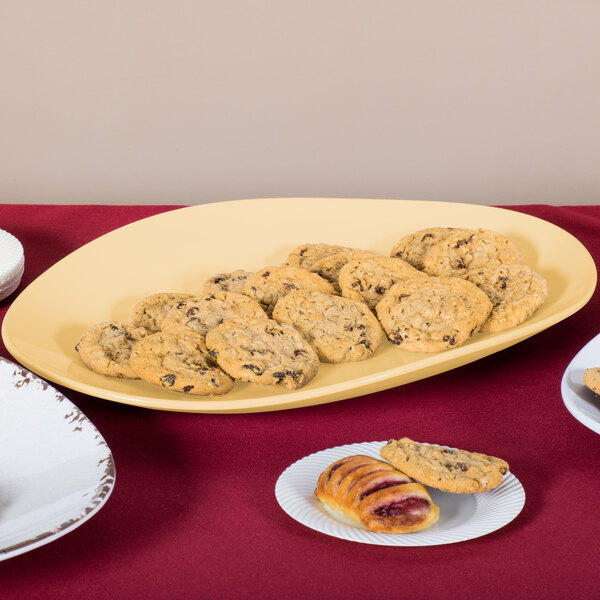 A table with a pile of cookies on a GET Dijon Flare oval melamine platter.
