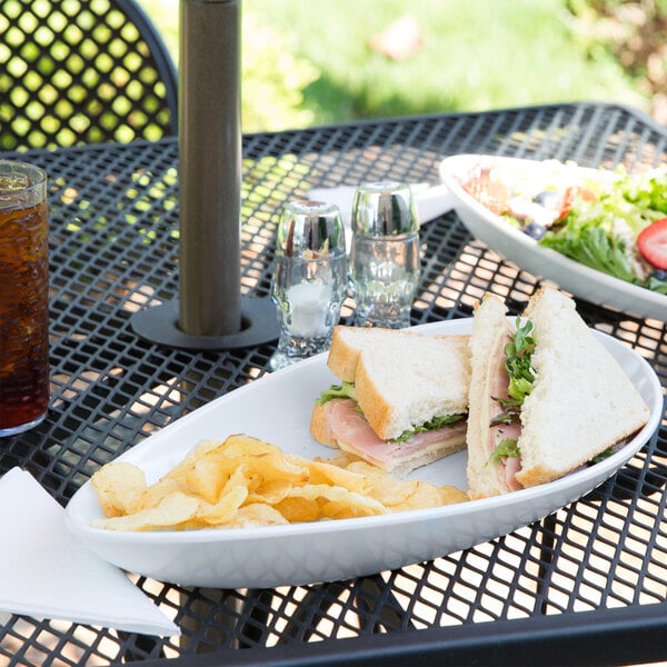 A white oval melamine platter with a sandwich and chips on it.
