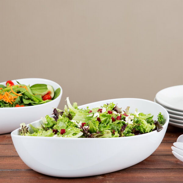 A table set with a bowl of salad and a stack of plates.