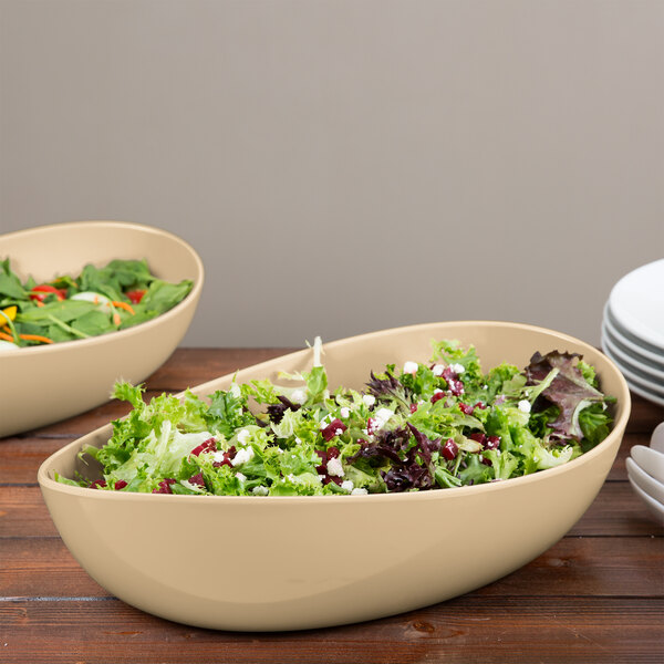 Two GET Osslo latte melamine bowls filled with salad on a table.