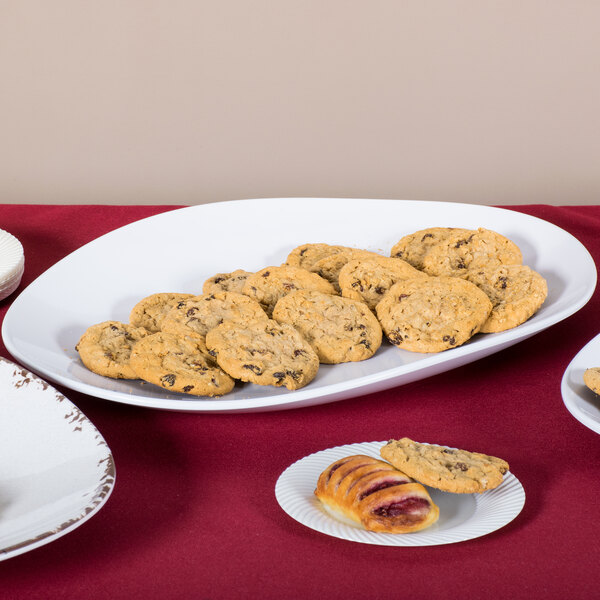 A white oval melamine platter with cookies on a table.