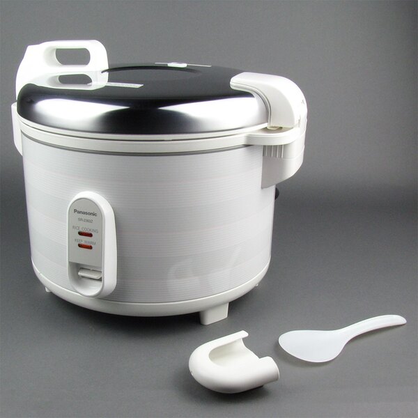 A white Panasonic commercial rice cooker with a black lid next to a white plastic spoon.