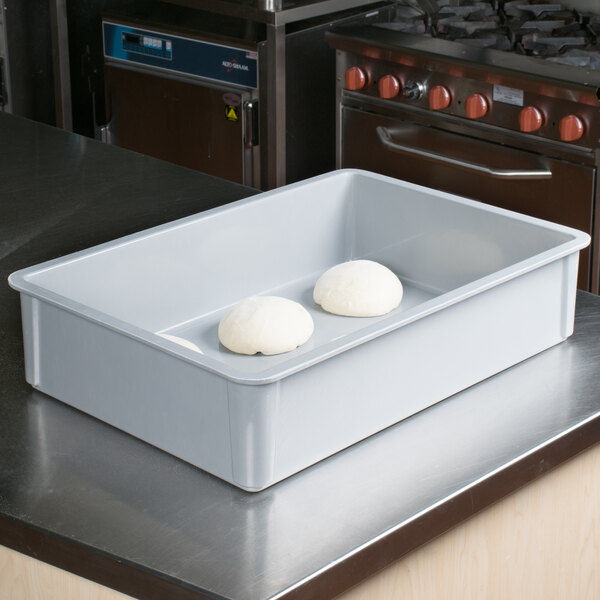 A MFG Tray gray fiberglass dough proofing box on a tray with two balls of dough in it.