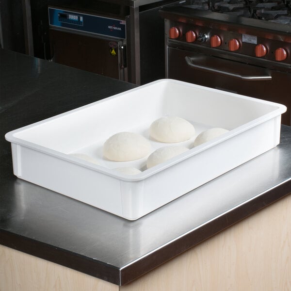 A white MFG Tray dough proofing box on a counter with round dough balls in it.