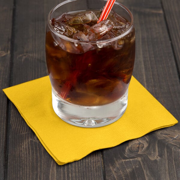 A glass of ice with a straw and a School Bus Yellow 2-ply beverage napkin.