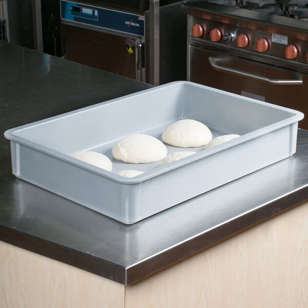 A gray MFG Tray fiberglass dough proofing box on a counter with white dough inside.