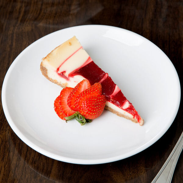 A slice of cheesecake with strawberries on a Libbey Porcelana coupe plate.