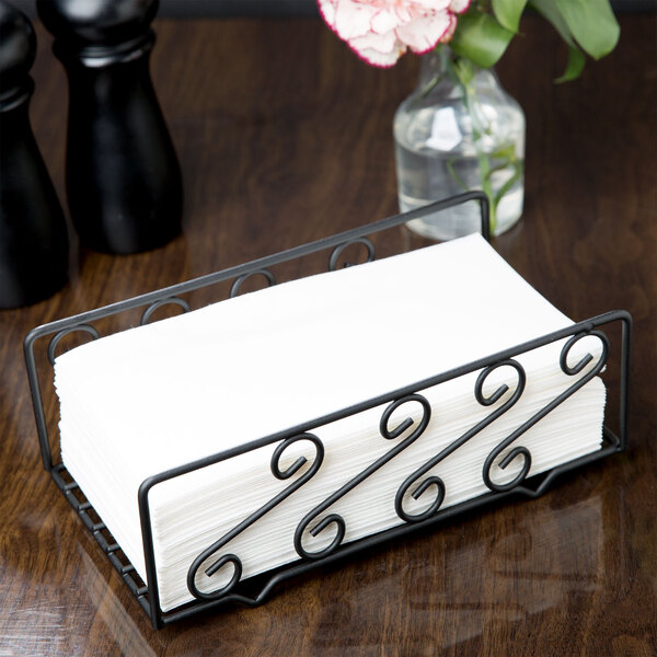 An American Metalcraft wrought iron scroll guest towel holder with white paper napkins on a counter.