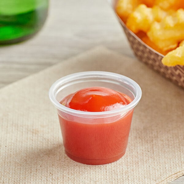 A small clear plastic Choice portion cup with red sauce in it.