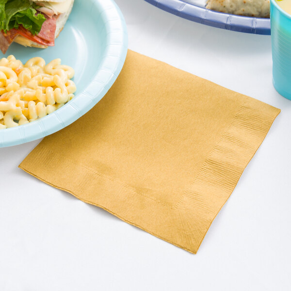 A blue plate with macaroni and cheese next to a Glittering Gold luncheon napkin.