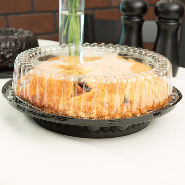A pie in a D&W Fine Pack plastic container with a clear high dome lid on a table in a bakery display.