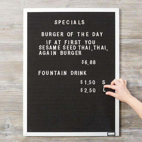 A hand pointing at black felt letter board with white letters that says "Specials: Burgers of the Day"