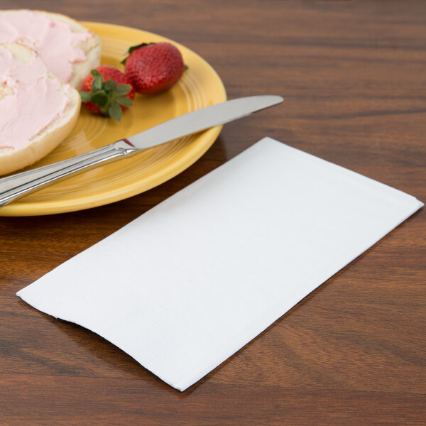 A plate with food and a white Creative Converting 3-ply guest towel on the table.