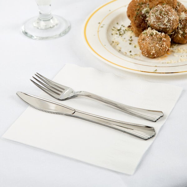 A plate of meatballs and a knife on a white 1/4 fold luncheon napkin.